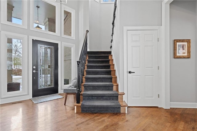 foyer with a high ceiling, wood finished floors, visible vents, baseboards, and stairway