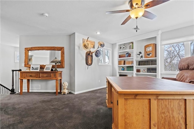 interior space featuring ceiling fan, dark colored carpet, visible vents, and baseboards