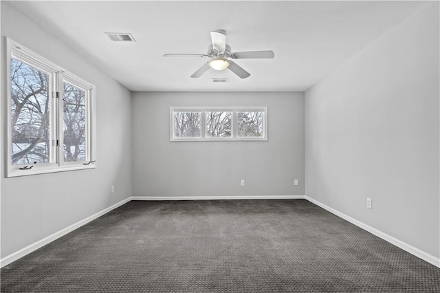 spare room featuring ceiling fan, dark carpet, visible vents, and baseboards