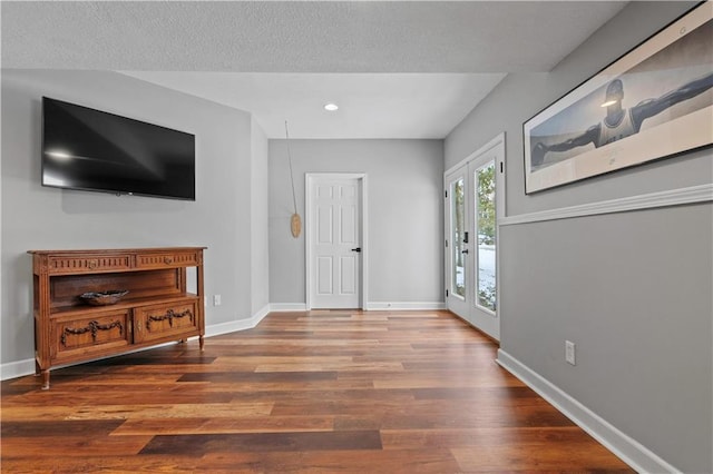 foyer featuring a textured ceiling, baseboards, wood finished floors, and recessed lighting