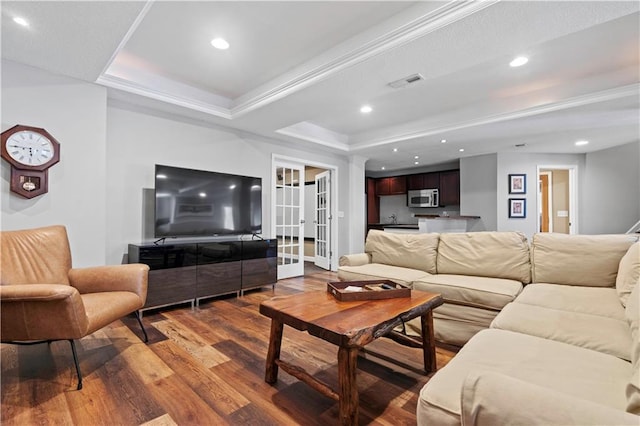 living room featuring visible vents, ornamental molding, dark wood-type flooring, a tray ceiling, and recessed lighting