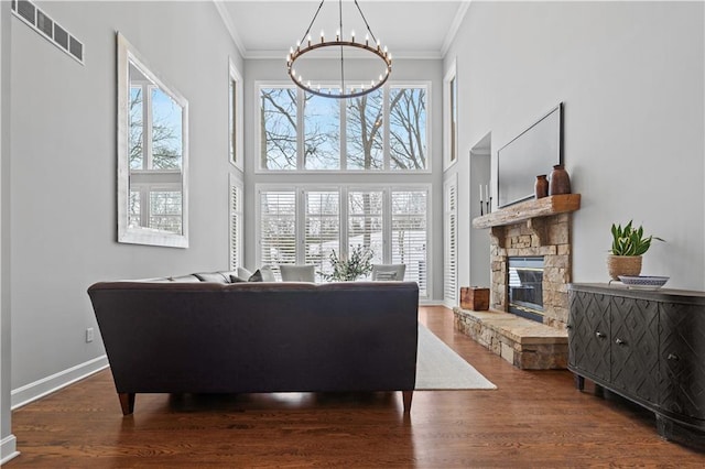 living room with a notable chandelier, visible vents, ornamental molding, wood finished floors, and baseboards