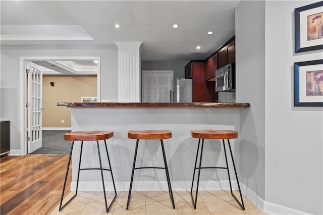 kitchen featuring baseboards, stainless steel appliances, recessed lighting, and a kitchen breakfast bar