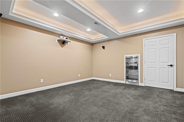 empty room featuring dark colored carpet, a raised ceiling, baseboards, and recessed lighting