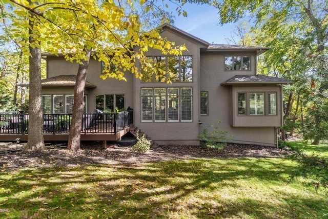 back of property featuring a wooden deck, a lawn, and stucco siding