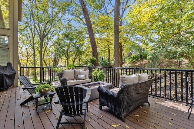 wooden deck with grilling area and an outdoor living space with a fire pit