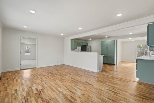 unfurnished living room with crown molding, light hardwood / wood-style flooring, and a wealth of natural light