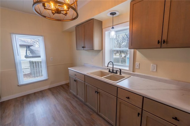 kitchen with sink, crown molding, wood-type flooring, a chandelier, and pendant lighting