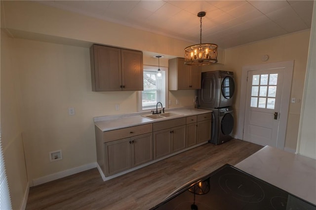 kitchen featuring stacked washer / drying machine, decorative light fixtures, dark hardwood / wood-style flooring, and sink