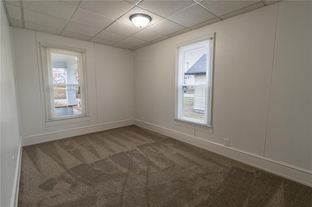 empty room with a paneled ceiling, a healthy amount of sunlight, and carpet flooring