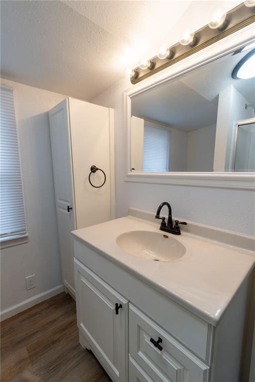 bathroom featuring vanity, hardwood / wood-style floors, an enclosed shower, and a textured ceiling