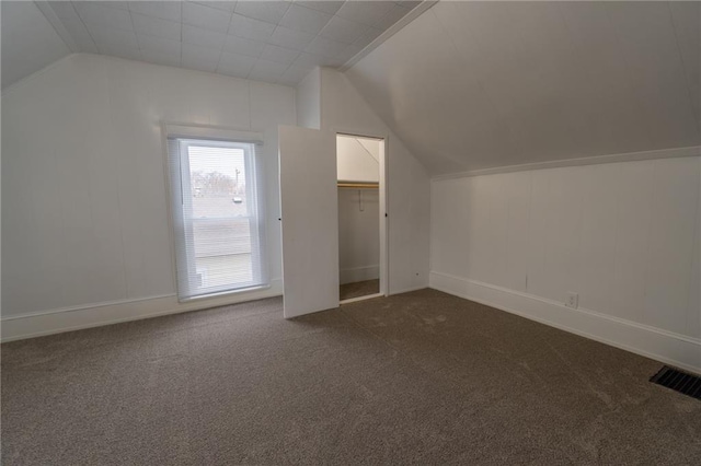 additional living space featuring lofted ceiling and dark colored carpet