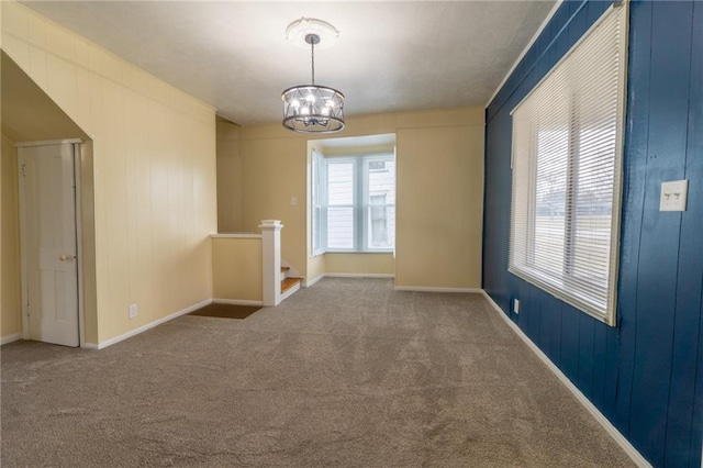 carpeted spare room featuring a notable chandelier