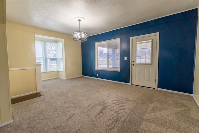 foyer with a wealth of natural light, light colored carpet, and an inviting chandelier