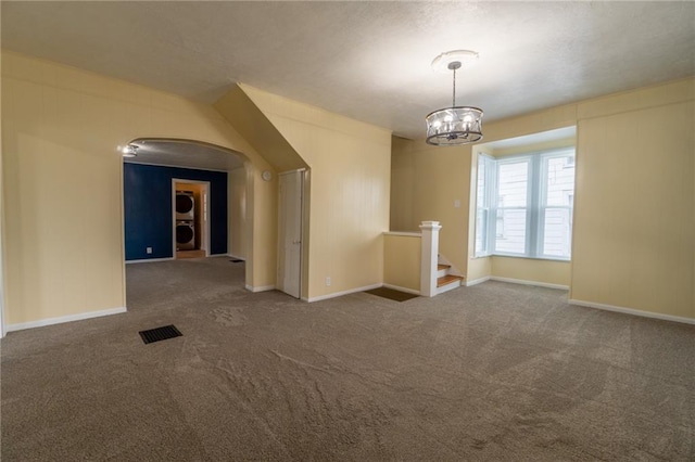 spare room featuring a chandelier and dark carpet