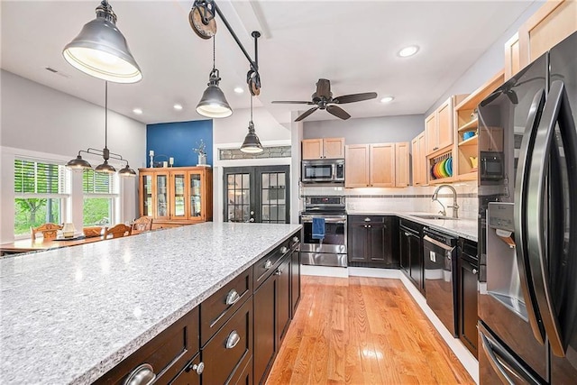 kitchen with sink, hanging light fixtures, backsplash, black appliances, and light brown cabinets