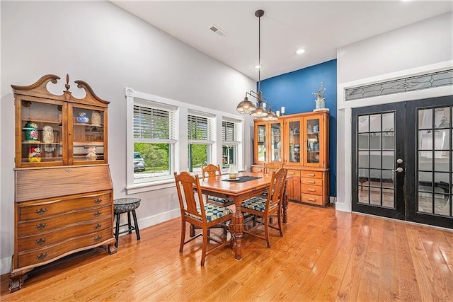 dining room with french doors, an inviting chandelier, and light hardwood / wood-style flooring