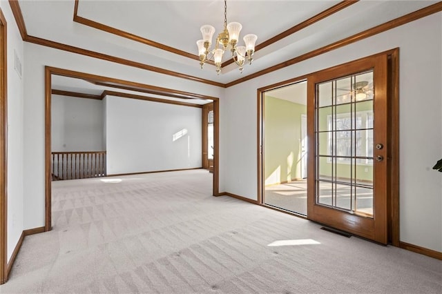 carpeted empty room featuring a tray ceiling, a notable chandelier, and crown molding