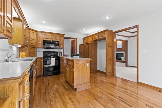 kitchen featuring sink, a center island, tasteful backsplash, black appliances, and light wood-type flooring