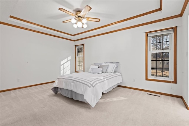 carpeted bedroom featuring crown molding, a tray ceiling, and ceiling fan