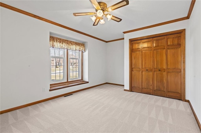 unfurnished bedroom featuring light carpet, ornamental molding, a closet, and ceiling fan