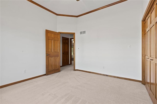 unfurnished bedroom with crown molding, a closet, light carpet, and a high ceiling