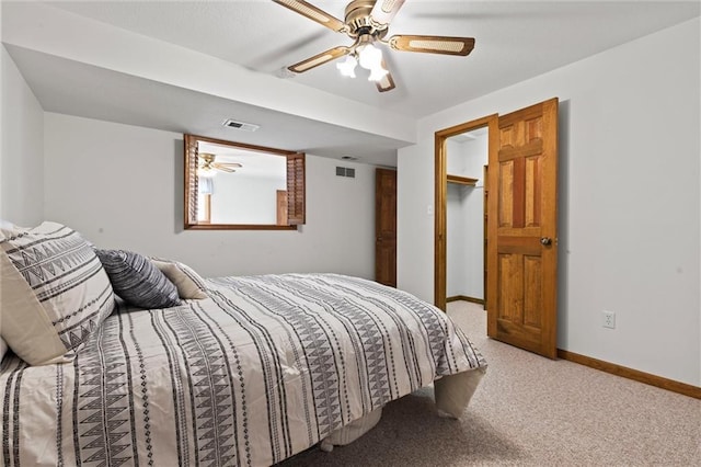 bedroom featuring a walk in closet, carpet floors, and ceiling fan