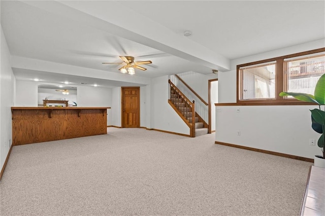 unfurnished living room featuring indoor bar, light colored carpet, and ceiling fan