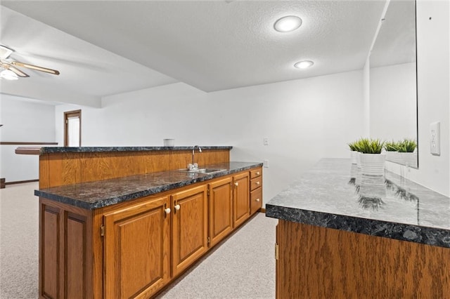 kitchen with light carpet, a center island, sink, and ceiling fan