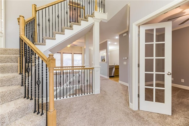 stairway featuring a high ceiling, ornamental molding, carpet, and french doors