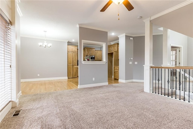 carpeted spare room featuring crown molding and ceiling fan with notable chandelier