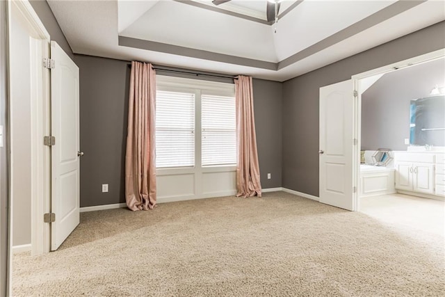 unfurnished bedroom with ceiling fan, light colored carpet, and ensuite bath