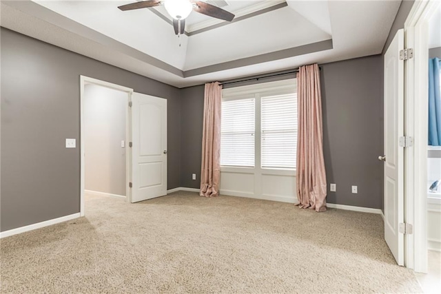 carpeted spare room featuring a tray ceiling and ceiling fan