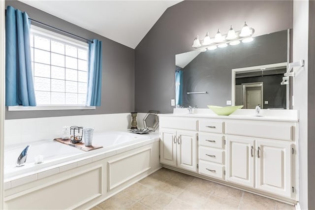 bathroom with lofted ceiling, vanity, tile patterned flooring, and a bathing tub