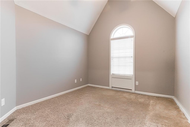 carpeted empty room featuring lofted ceiling and plenty of natural light