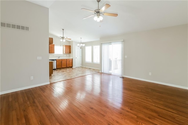 unfurnished living room with hardwood / wood-style flooring, sink, vaulted ceiling, and ceiling fan with notable chandelier