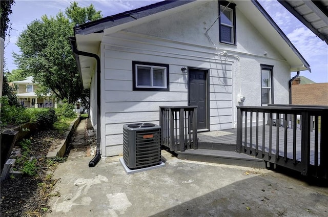 rear view of property featuring central AC unit and a wooden deck