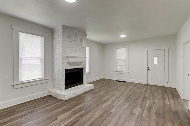 unfurnished living room featuring hardwood / wood-style floors and a stone fireplace