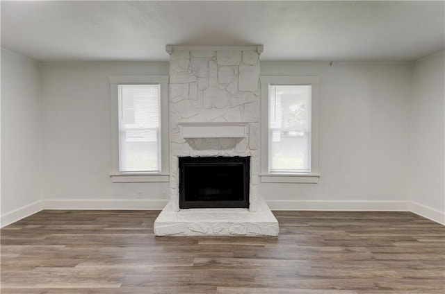 unfurnished living room featuring hardwood / wood-style flooring and a stone fireplace