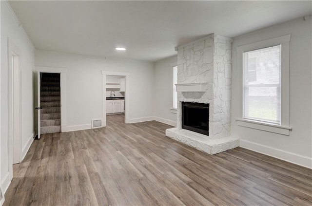 unfurnished living room featuring a fireplace, sink, and light hardwood / wood-style flooring