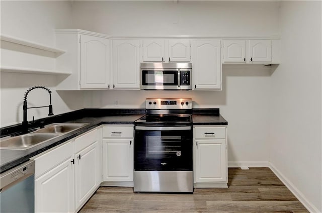 kitchen with appliances with stainless steel finishes, light hardwood / wood-style flooring, white cabinetry, and sink