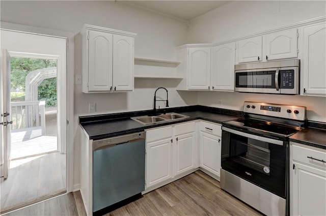 kitchen with appliances with stainless steel finishes, light hardwood / wood-style floors, white cabinets, and sink