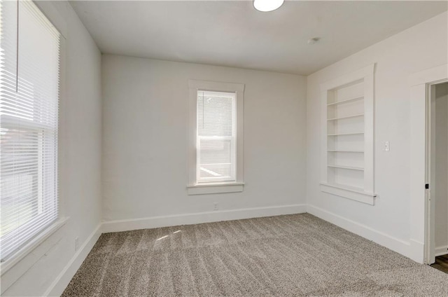 spare room with built in shelves and carpet