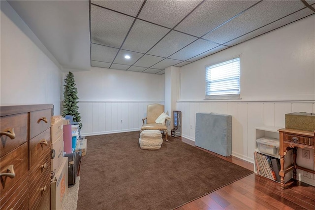 living area featuring wood-type flooring and a drop ceiling