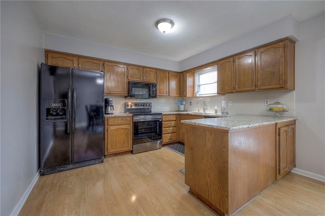 kitchen featuring sink, tasteful backsplash, light hardwood / wood-style floors, black appliances, and kitchen peninsula