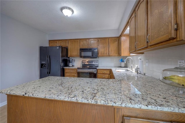 kitchen featuring light stone countertops, sink, kitchen peninsula, and black appliances