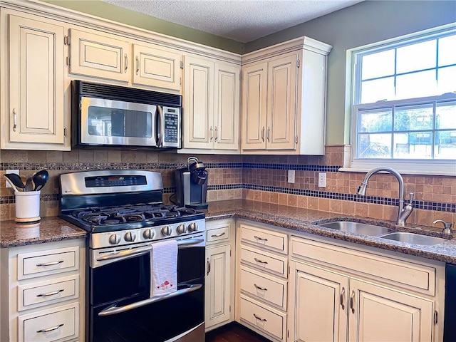 kitchen with tasteful backsplash, cream cabinets, stainless steel appliances, and sink