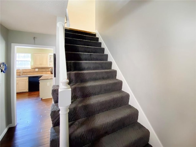 staircase with wood-type flooring and sink