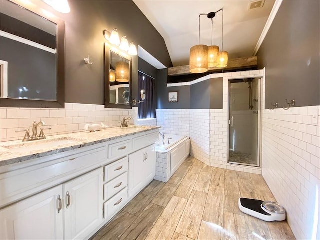 bathroom with tile walls, vanity, lofted ceiling, and shower with separate bathtub