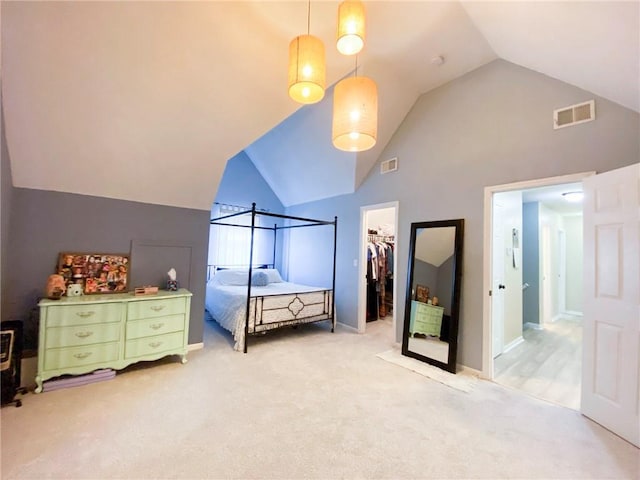 bedroom featuring a closet, a spacious closet, high vaulted ceiling, and light carpet